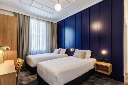 two beds in a hotel room with blue walls at Royal Exhibition Hotel in Sydney