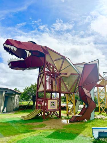 a playground with a dinosaur shaped play structure at 女性専用ゲストハウス与那原 in Yonabaru