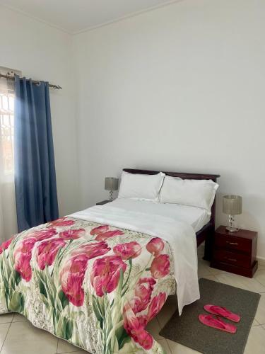 a bedroom with a bed with pink flowers on it at 3Bedroom Hilltop Home In Muyenga in Kampala