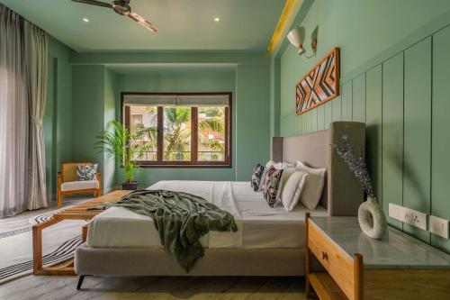 a bedroom with green walls and a bed and a desk at Raina Villas Goa 6 bhk lux Pvt Pool in Arpora