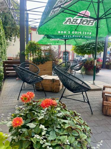 a patio with chairs and flowers and a green umbrella at ART Pensjonat in Krotoszyn