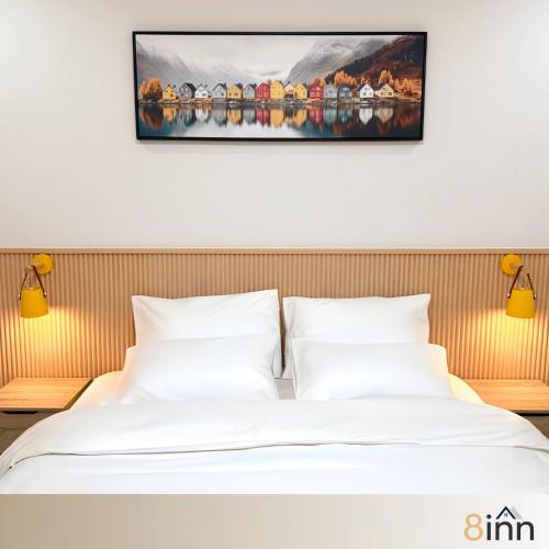 a bed in a hotel room with a painting on the wall at 8inn hostel