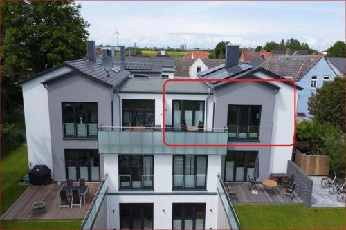 a large white house with a red line on it at Exclusives Appartement auf Fehmarn in Petersdorf auf Fehmarn