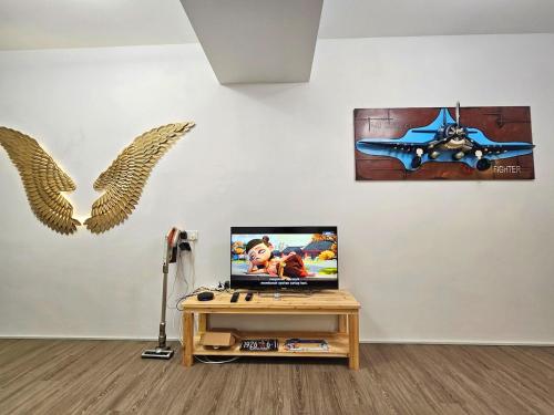 a room with a table with a tv and wings on the wall at Propeller Airplane Riverview Kuching Homestay in Kuching