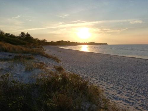 a beach with the sun setting on the water at 5 star holiday home in Dronningmølle in Dronningmølle