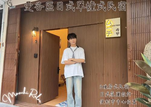 a young man standing in front of a door at Moochi Home Ratchada in Bangkok