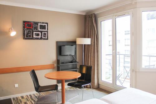 a room with a table and chairs and a tv at Bright studio apartment with parking and balcony in Issy-les-Moulineaux
