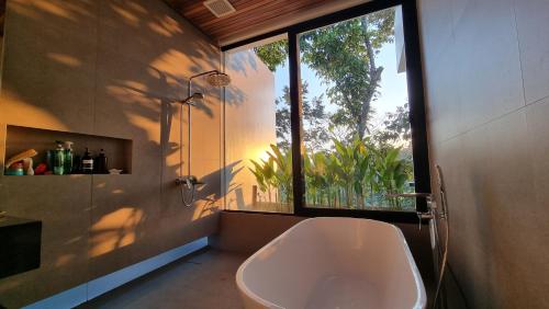 a bathroom with a bath tub and a window at Maxwell Villa Bali in Tabanan