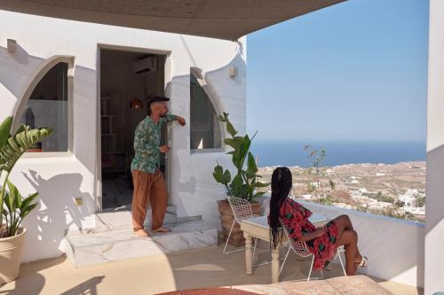 a man and a woman sitting on the porch of a house at Canyon Santorini in Fira