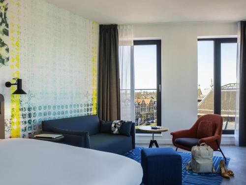 a hotel room with a bed and a couch and chairs at ibis Styles Delft City Centre in Delft