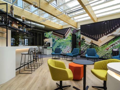 a bar with chairs and tables and a mural at ibis Styles Delft City Centre in Delft