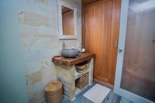 a bathroom with a sink and a stone wall at Moonlight Villa Close By Blue Lagoon in Nusa Ceningan