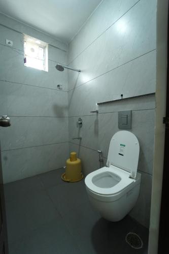 a bathroom with a white toilet and a window at Nandan Enclave in Mysore