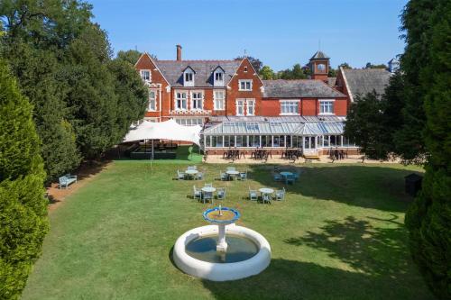 an aerial view of a large house with a fountain in the yard at DoubleTree by Hilton St. Anne's Manor in Bracknell