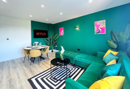 a living room with a green couch and a table at Luxury Norwich City Centre Apartment - Free Parking in Norwich