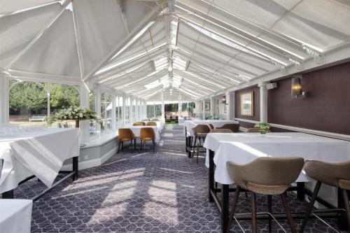 a dining room with white tables and chairs at DoubleTree by Hilton St. Anne's Manor in Bracknell