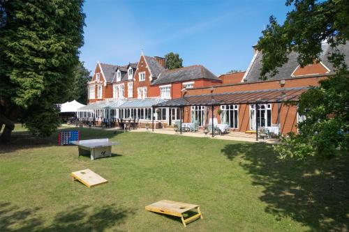 a large building with a yard with benches in front of it at DoubleTree by Hilton St. Anne's Manor in Bracknell