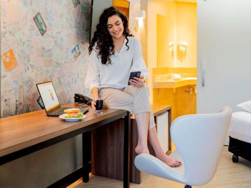 a woman sitting on a desk in a room at ibis Styles Sorocaba Santa Rosalia in Sorocaba
