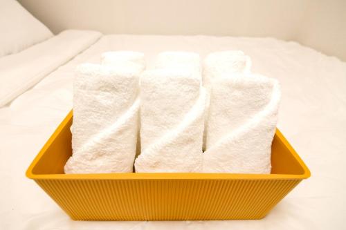 a yellow basket filled with white towels on a bed at wonjong stay 101 김포공항 in Pakkosi