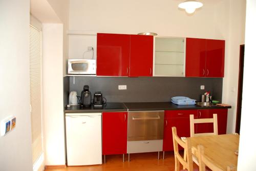 a small kitchen with red cabinets and a table at Apartmán Jeseník in Jeseník