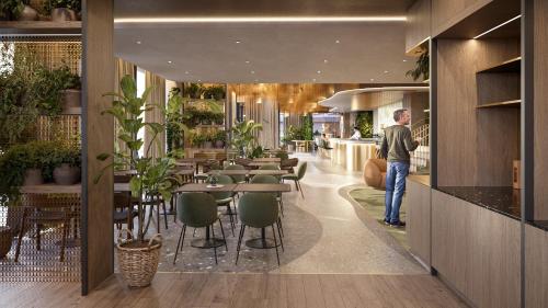 a man standing in a restaurant with tables and chairs at Novotel Tallinn in Tallinn