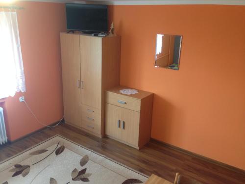 a bedroom with orange walls and a cabinet and a television at Kwatera Pod Lasem in Istebna