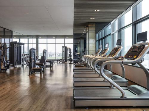 a gym with a row of treadmills and machines at Pullman Jiaxing Pinghu Excellence in Jiaxing