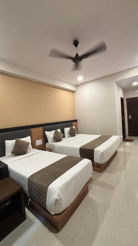 a bedroom with two beds and a ceiling fan at Hotel Kalyan Suites in Bengaluru