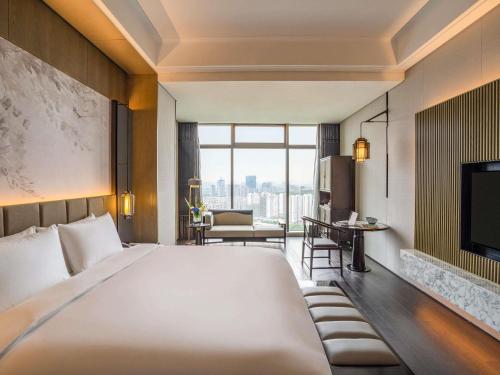 a hotel room with a large bed and a television at Sofitel Hangzhou Yingguan-Olympic Center Hotel in Hangzhou