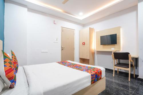 ハイデラバードにあるFabHotel Orion - Nr Shilparamam, Hi tech cityのベッドと椅子とテレビのある寝室