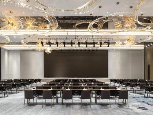 a large room with tables and chairs and a projection screen at Sofitel Hangzhou Yingguan-Olympic Center Hotel in Hangzhou