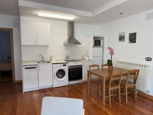 a kitchen with white appliances and a table with chairs at Apartamentos Pirineo in Isaba