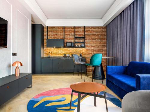 a living room with a blue couch and a kitchen at Mercure Krakow Fabryczna City in Kraków