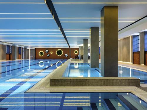 a swimming pool in a building with blue ceilings at Mercure Krakow Fabryczna City in Kraków