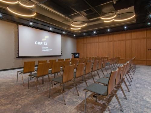 a conference room with a projector screen and chairs at Mercure Krakow Fabryczna City in Kraków