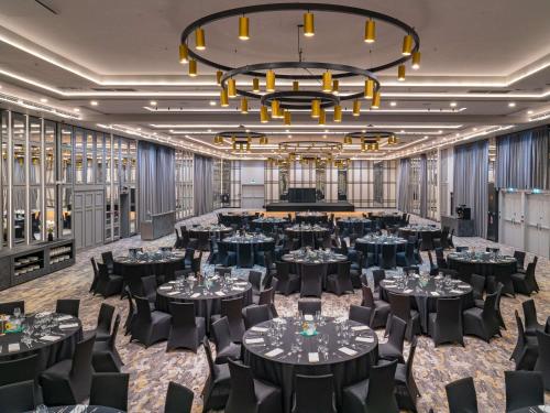 a ballroom with tables and chairs and a large chandelier at Mercure Krakow Fabryczna City in Kraków