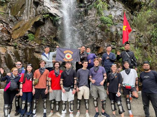 a group of people standing in front of a waterfall at Sunflower House - Ha Giang Loop Tour in Bản Kin