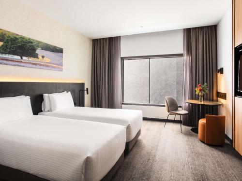 a hotel room with two beds and a window at Mövenpick Hotel Hobart in Hobart