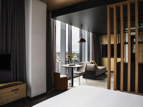 a hotel room with a bed and a table with a view at Mövenpick Hotel Hobart in Hobart