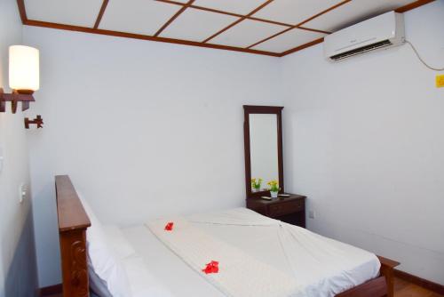a bedroom with a white bed and a mirror at Villa Thotiya in Aluthgama