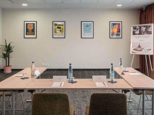 a meeting room with tables and chairs and a screen at Mercure Belfort Centre in Belfort