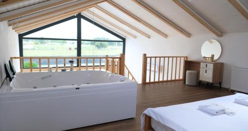 a large white bath tub in a room with a large window at Terra Viva Villa's in Erenköy