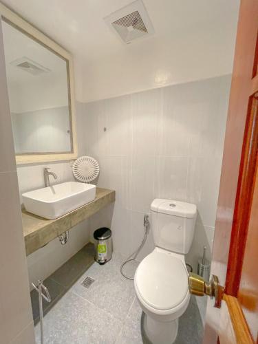 a bathroom with a white toilet and a sink at The Blue Doors- Siargao in General Luna