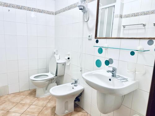 a white bathroom with a toilet and a sink at Penzion Chalupa U Městské brány in Vyškov