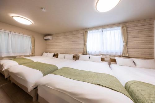 a group of four beds in a room with windows at Amp Flat ブラン呉服 in Fukuoka