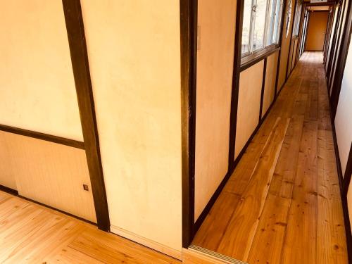 an empty hallway with wood floors and a window at 料理自慢の温泉宿せせらぎ荘 in Chichibu