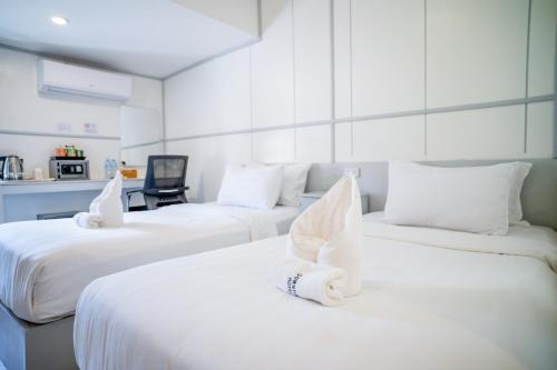 a room with three beds with white sheets at DownTown Hotel in Luang Prabang