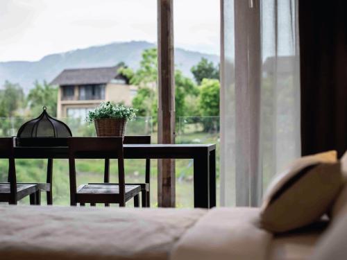a bedroom with a table and chairs and a window at Atta Lakeside Resort Suite - SHA Plus Certified in Mu Si