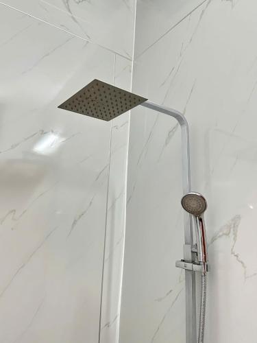a shower in a bathroom with white marble walls at Window 2 Hotel in Kon Tum