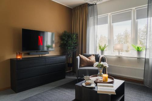 a living room with a tv and a couch and a chair at Guestly Homes - Homely 1BR Apartment in Luleå
